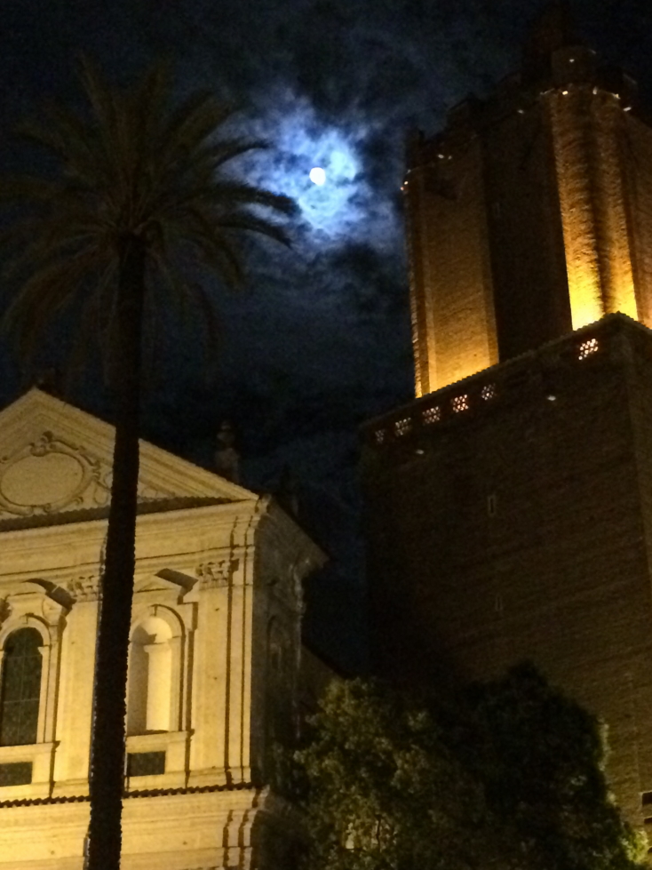 Torre della Milizie illuminated by the full moon on a partly cloudy night