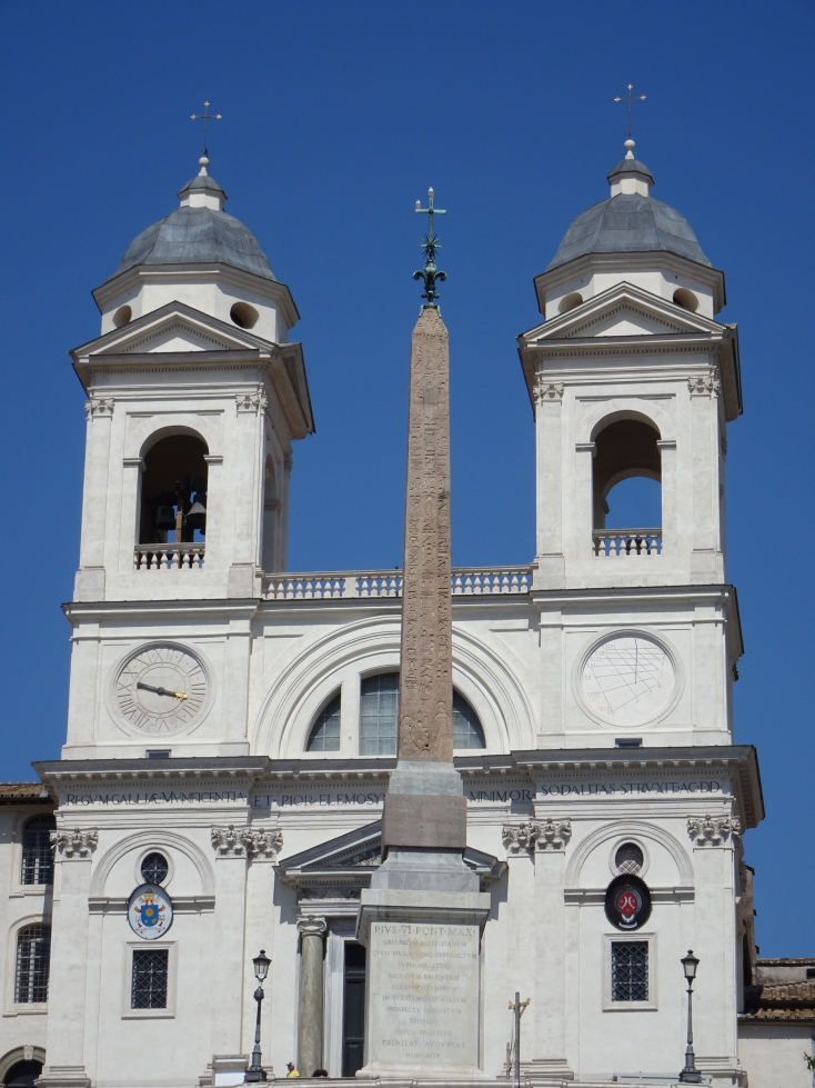 The obelisk and church at the top of the Spanish Steps in the afternoon sun